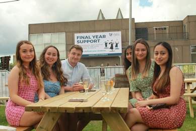 students sat at a table with drinks and picnic